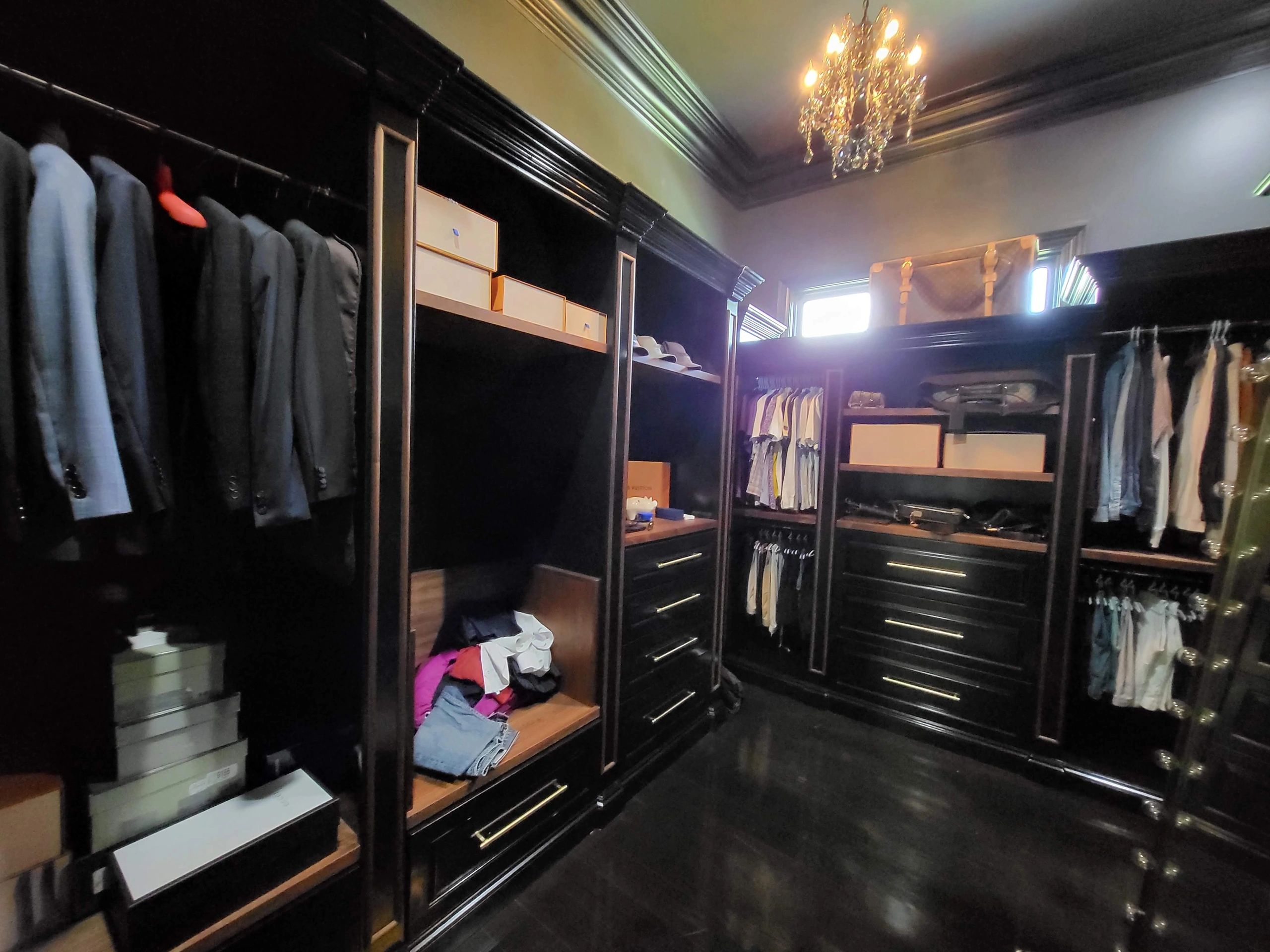 Finished dark wood walk-in closet with custom cabinets and lighting