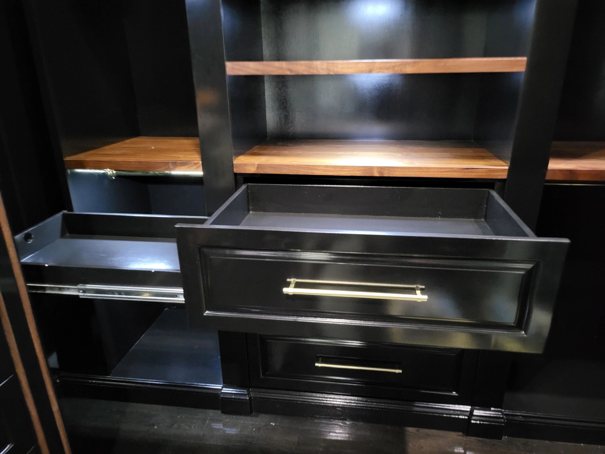 Custom black cabinetry with wood shelves and brass hardware